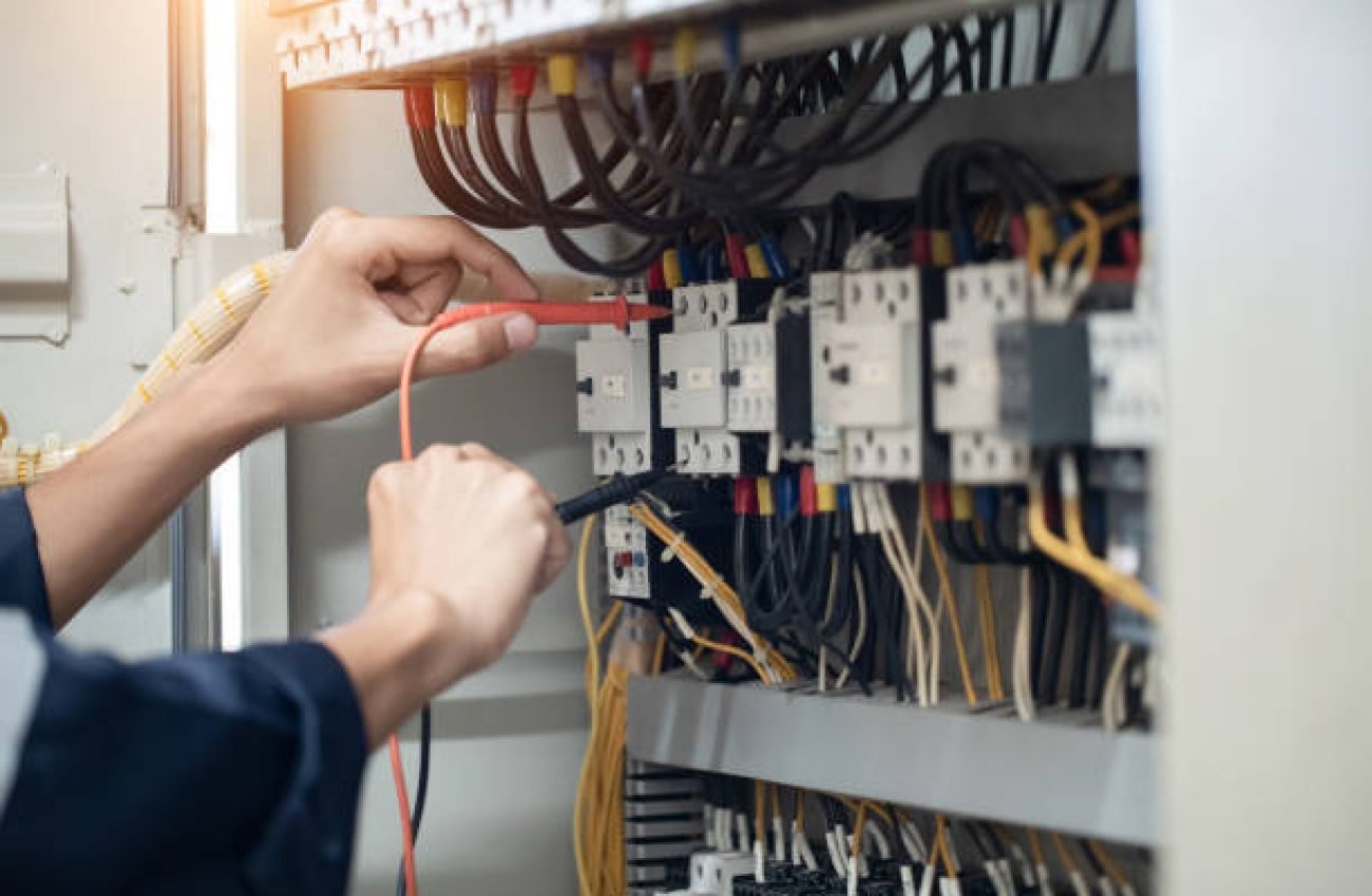Electrician engineer work tester measuring voltage and current of power electric line in electical cabinet control , concept check the operation of the electrical system .